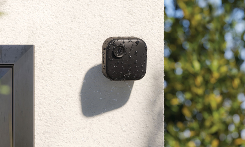 Image of Blink's Outdoor Camera 4, attached to a white rendered concrete wall covered in water droplets from a recent shower. 