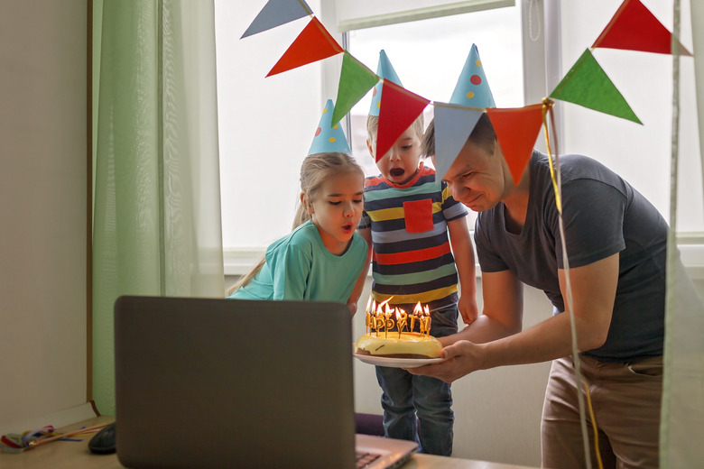 Happy family with two sibling celebrating birthday via internet in quarantine time, self-isolation and family values, online birthday party, selective focus on cake