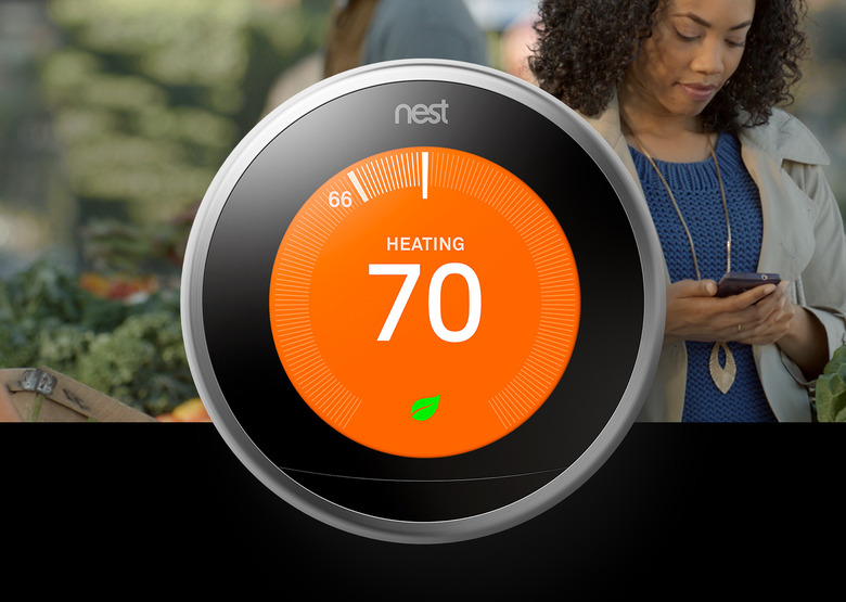 Google promo image for its Nest Learning Thermostat. Foreground: the circular device with a round screen (orange, reading 