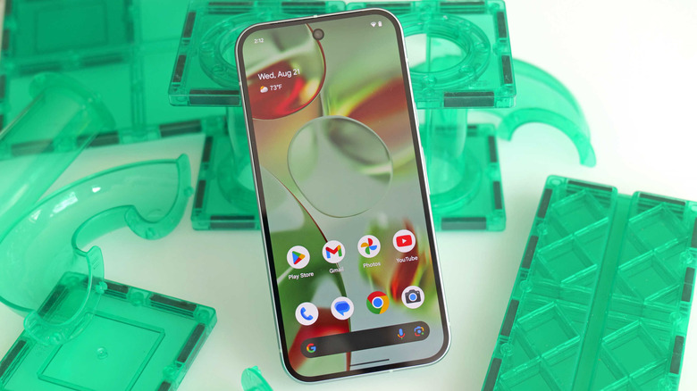Photo of the Google Pixel 9 smartphone with funky green stuff in the background.
