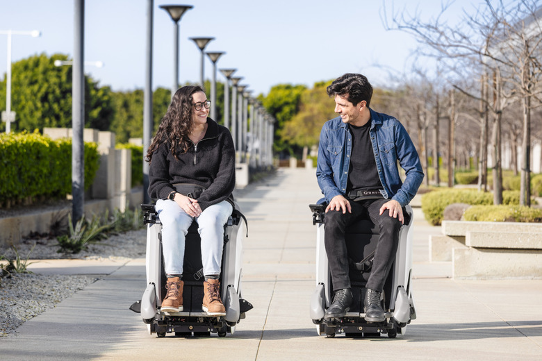 Two people sitting on high-tech chairs in the park.