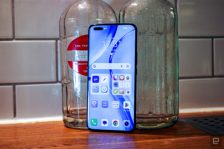 Image of Honor's Magic 5 Pro leaning against glass bottles.