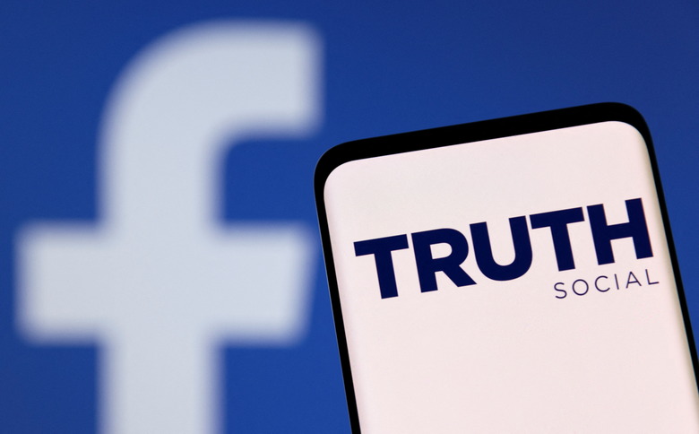 The Truth social network logo is seen on a smartphone in front of a display of the Facebook logo in this picture illustration taken February 21, 2022. REUTERS/Dado Ruvic/Illustration