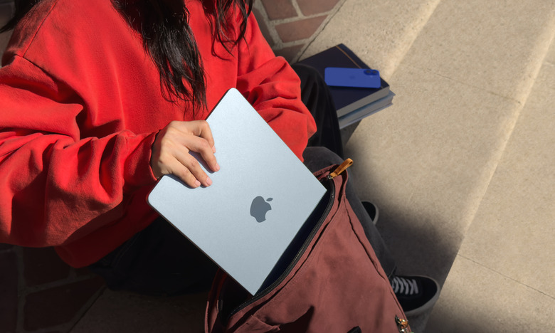 Lifestyle marketing photo of a person sliding the MacBook Air into a backpack.
