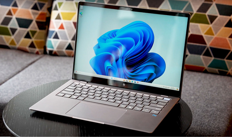 A silver HP Omnibook X sitting on a round table with its screen and keyboard facing the camra.