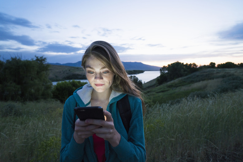 Teenage girl using her smart phone while hiking