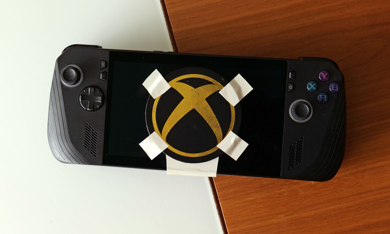 A black and gold Xbox logo duct-taped onto the screen of a gaming handheld device.