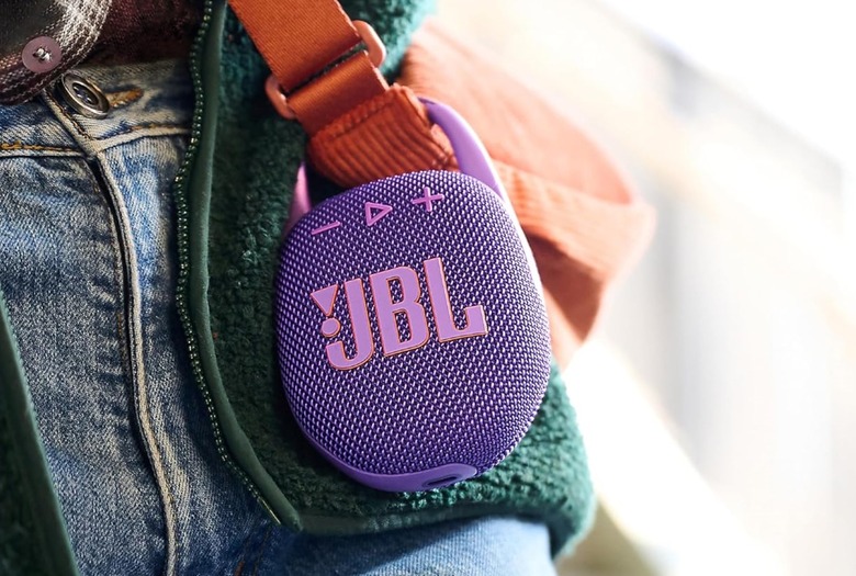 JBL Clip 5 Bluetooth speaker attached to a bag strap.