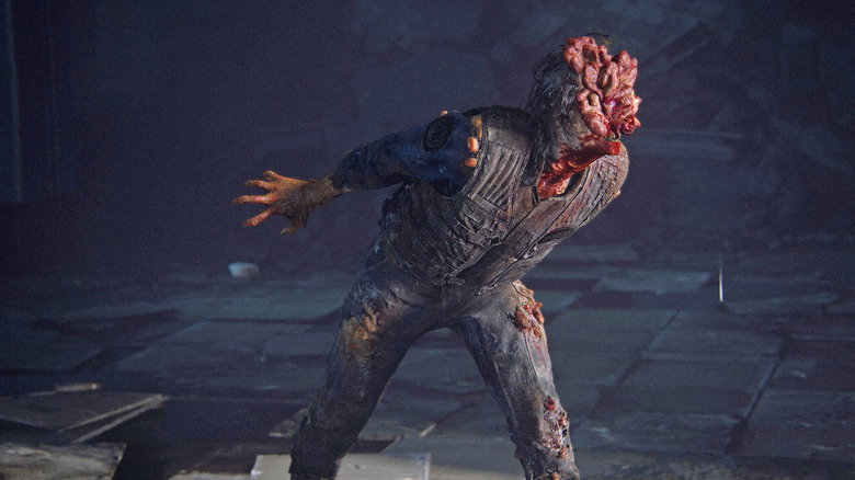 An image from the video game 'The Last of Us Part 1' showing a humanoid creature with a fleshy stump for a head and sharp teeth lurching towards the camera.