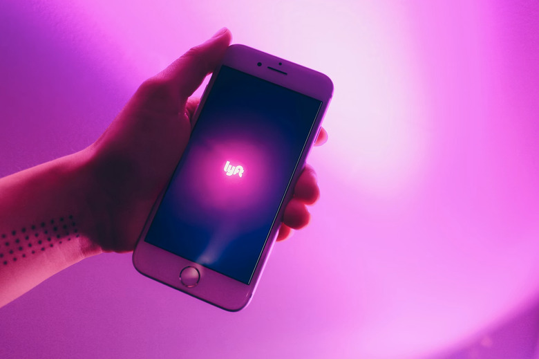 A person holding the Lyft app on a phone.