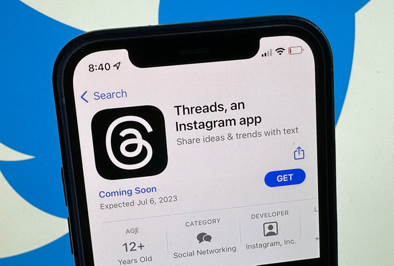 04 July 2023, Berlin: The announcement of the social media app Threads is displayed in Apple's US App Store. The Twitter logo can be seen in the background. The eagerly awaited Twitter competitor from Facebook Group Meta is scheduled to launch on July 6, 2023.      (to dpa 