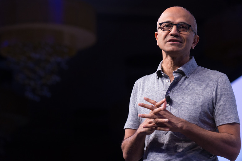 A man wearing a polo shirt and a pair of glasses with his hands clasped in front of him. 