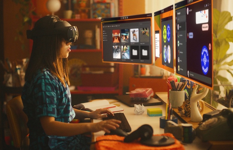 A person with long hair wearing a headset and looking at three floating virtual screens.