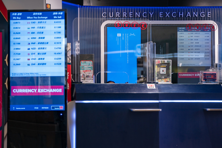 HONG KONG, CHINA - JULY 19: A error blue screen is displayed at a currency exchange store at the Hong Kong International Airport on July 19, 2024 in Hong Kong, China. A significant Microsoft outage impacted users globally, leading to widespread disruptions, including cancelled flights and disruptions at retailers globally. Airlines like American Airlines and Southwest Airlines reported difficulties with their systems, which rely on Microsoft services for operations. The outage affected check-in processes and other essential functions, causing frustration among travellers and lines to back up at many affected airports worldwide. (Photo by Anthony Kwan/Getty Images)