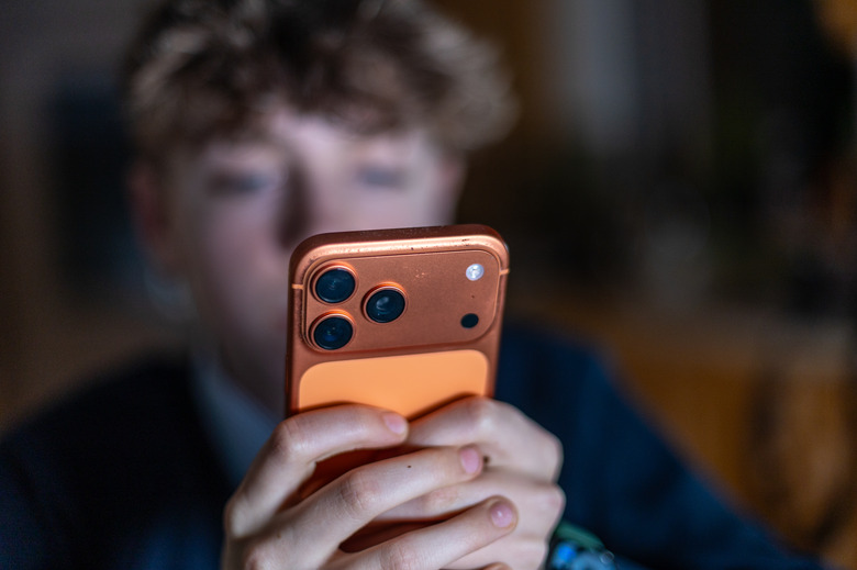 In this photo illustration a 14-year-old boy holds an iPhone screen displaying various social media and messaging apps on February 23, 2026 in Bath, England. (Photo by Anna Barclay/Getty Images)