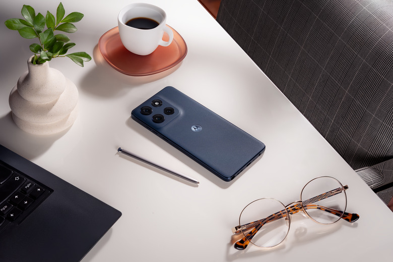 The Moto G stylus phone and its stylus on a desk next to a laptop and glasses.