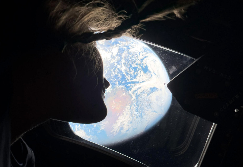 An astronaut looking out of a window at Earth.