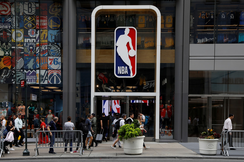 FILE PHOTO: The NBA logo is displayed as people pass by the NBA Store in New York City, U.S., October 7, 2019. REUTERS/Brendan McDermid/File Photo