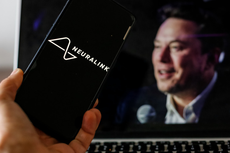 POLAND - 2024/05/23: In this photo illustration, the Neuralink logo is seen displayed on a smartphone screen with a computer screen displaying a portrait of Elon Musk, who is the owner of Neuralink. The company is looking for new volunteers for its Neuralink implants. (Photo Illustration by Dominika Zarzycka/SOPA Images/LightRocket via Getty Images)