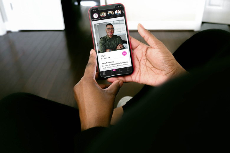 Someone holding up a smartphone with OkCupid app open.