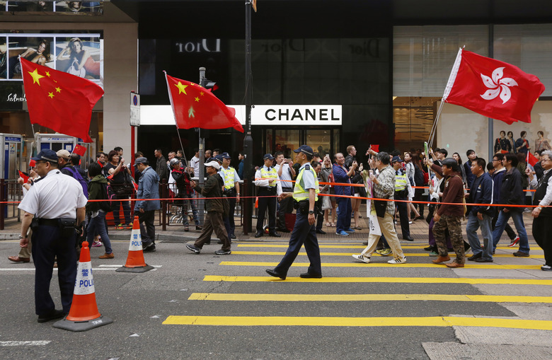 Pro-Chinese protesters, carrying Chinese flags and a Hong Kong flag, take part in a rally against hostility towards mainland Chinese, on Canton Road at the Tsim Sha Tsui shopping district in Hong Kong, March 15, 2015. Hong Kong retailers' sales in January were the lowest since 2003 and revenue growth this year will likely be the slowest in at least four years, hit by a drop in visitors from the mainland who have been put off in part by rising hostility among Hong Kongers. REUTERS/Bobby Yip  (CHINA - Tags: POLITICS BUSINESS CIVIL UNREST)