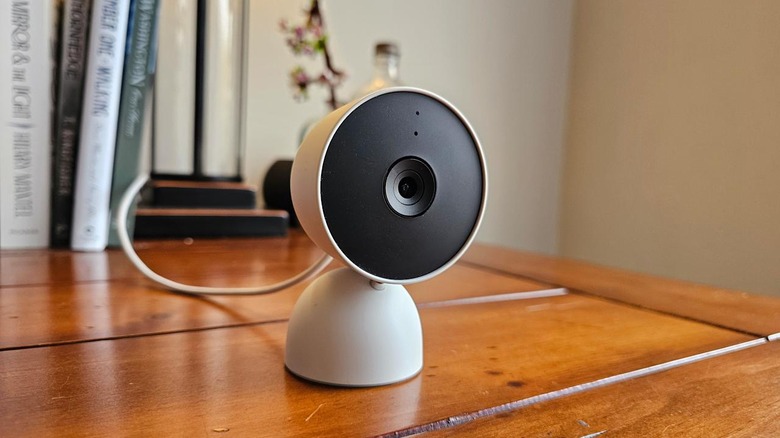 Photo of the Google indoor Nest Security Cam sitting on a desk with books in the background.