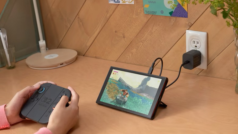 Someone playing a Switch 2 with its kickstand out and Joy-Con 2 controllers detached and slotted into a grip.