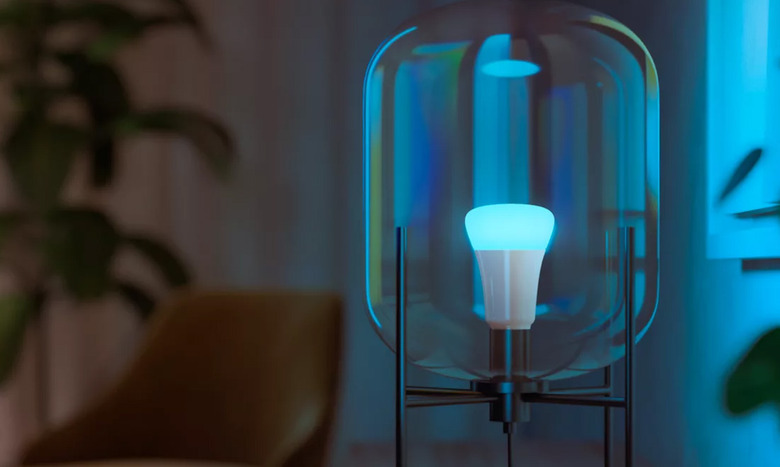 A Philips Hue smart bulb glowing blue inside a modern light fixture.