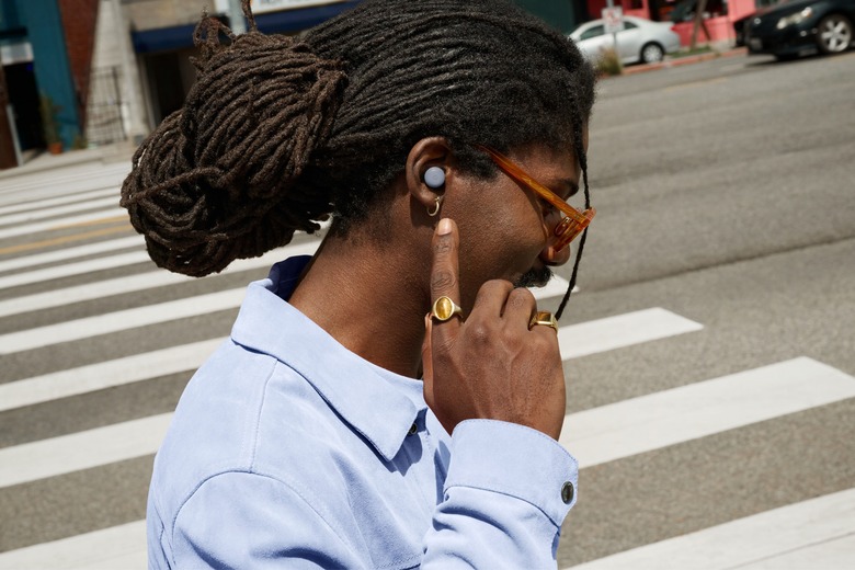 A person wearing Pixel Buds 2 in a gray variant in their ear