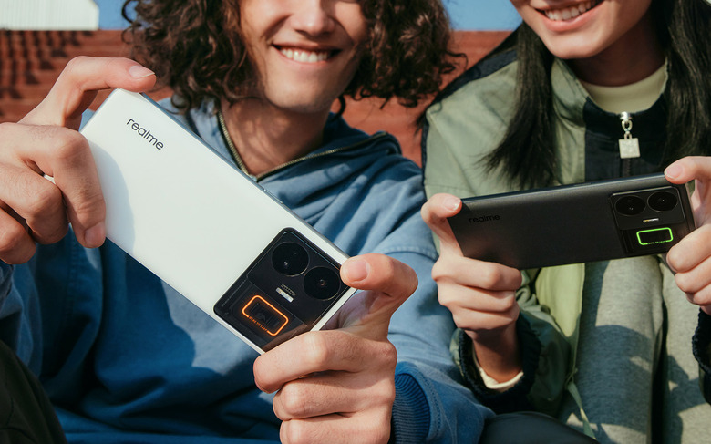 A user gaming on a white Realme GT3 in landscape orientation, while the other user is doing the same but with a black version.