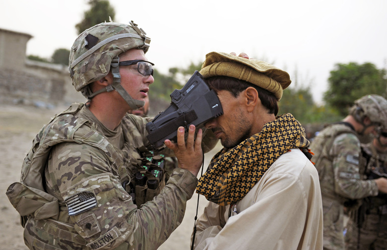 An American ISAF solider from team Apache of Task Force Geronimo, 4th Platoon Delaware of the United States Army,  collects biometric information from an Afghan villager in the village of Mans Kalay in Sabari, Khost district on August 4, 2012. ISAF has noted a surge in attacks in recent months since the start of the Taliban's annual summer offencive. 