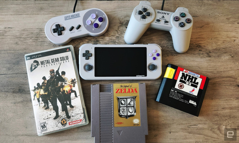 The Retroid Pocket 3 gaming handheld surrounded by old gaming cartridges and wired controllers.