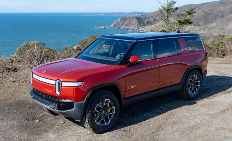Photo of the Rivian R1S electric SUV. It sits in a dirt parking area overlooking a beach.