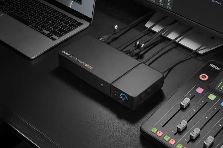 Image of the Rodecaster Video Core on. desk next to a MacBook and a Rodecaster Pro 2