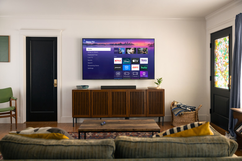 Roku Plus Series TV mounted on a wall in a living room.