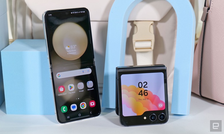 A Galaxy Z Flip 5 leaning against a pastel blue cube with its inside screen facing the camera, next to another Galaxy Z Flip 5 folded in half and propped up with its outside display facing the camera.