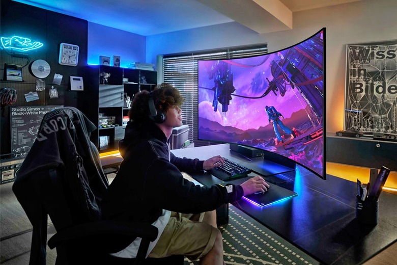 Product lifestyle photo of a young person playing a game on the Samsung 55-inch Odyssey Ark monitor. The enormous monitor curves around his head for an immersive view, as he games on his PC in a stylish modern gaming room.