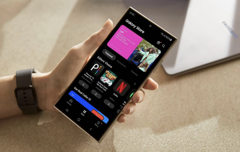 A hand holding a phone with its open showing the Samsung Galaxy Store.