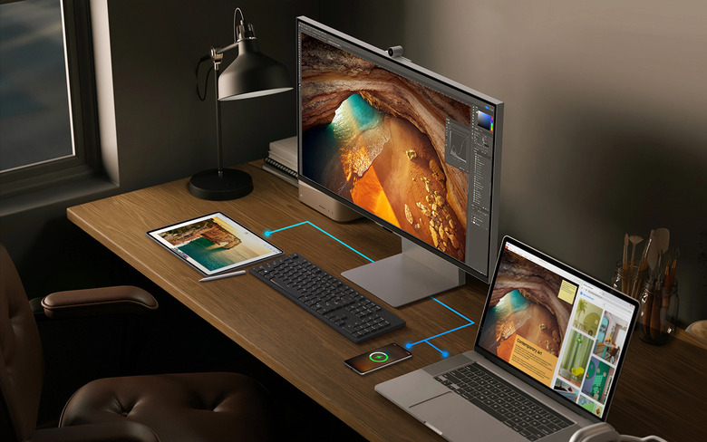 A monitor, a keyboard, a laptop and a tablet on top of a wooden table.
