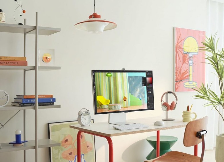 Large computer screen on desk with chair. 