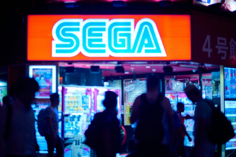 A group of people walk past a Sega sign.