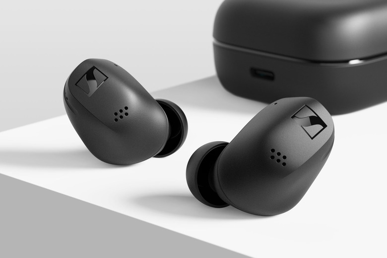 Sennheiser Accentum True Wireless earbuds in black sitting on a white surface with the charging case in the background.