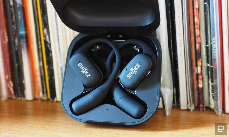 Close-up images of the Shokz OpenFit open-ear buds in grey with the charging case.