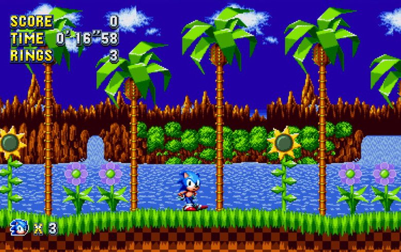 A screenshot of Sonic Mania Plus showing Sonic, an anthropomorphic blue hedgehog, against a background of computer-drawn beach and palm trees. 
