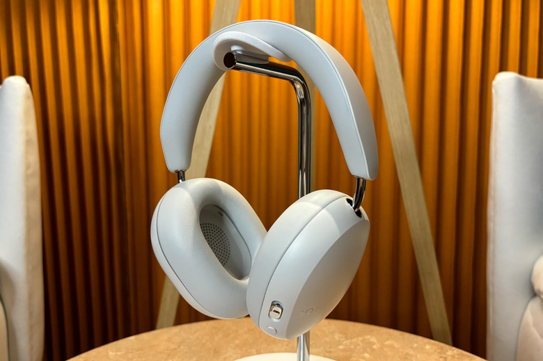 White headphones on stand sitting on a small table. 
