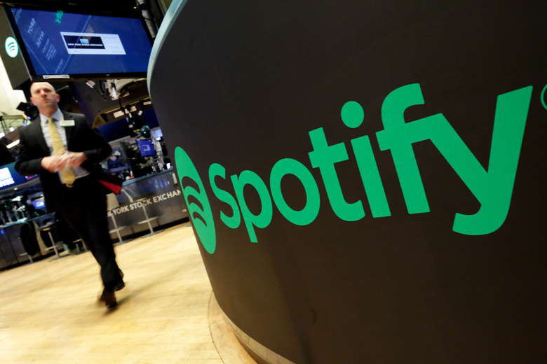 FILE - A trading post sports the Spotify logo on the floor of the New York Stock Exchange, Tuesday, April 3, 2018. Spotify said Monday, Dec. 4, 2023 it's axing 17% of its global workforce, in the music streaming service's third round of layoffs this year as it tries to slash costs while focusing on profitabilty. (AP Photo/Richard Drew, File)