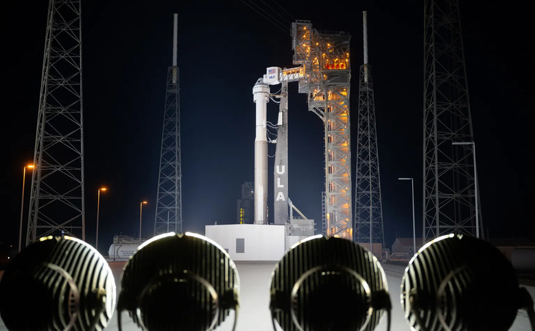 Starliner sitting atop a ULA Atlas V rocket on the launch pad at night