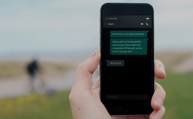 A person holds up a phone with text messages sent via Starlink's satellite network.