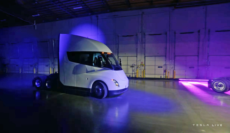 The Tesla Semi delivery event showing a Semi trailer in a dark warehouse with dramatic purple and blue lighting.