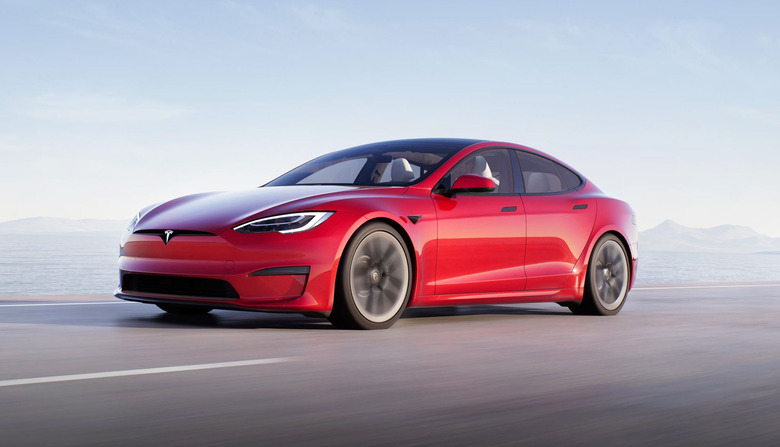 A Tesla Model S Plaid in red races down a coastal highway.